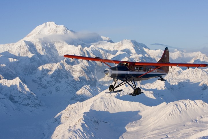 A small plane flies next to snow covered Mt. Denali.