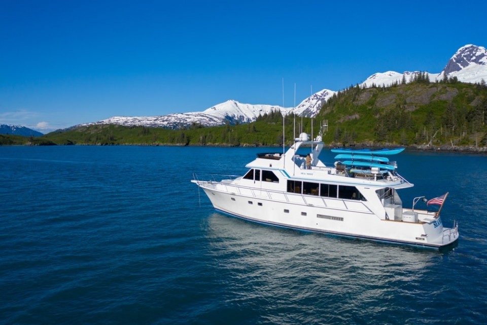 A luxury yacht sails along Prince William Sound with snow capped mountains in the background.
