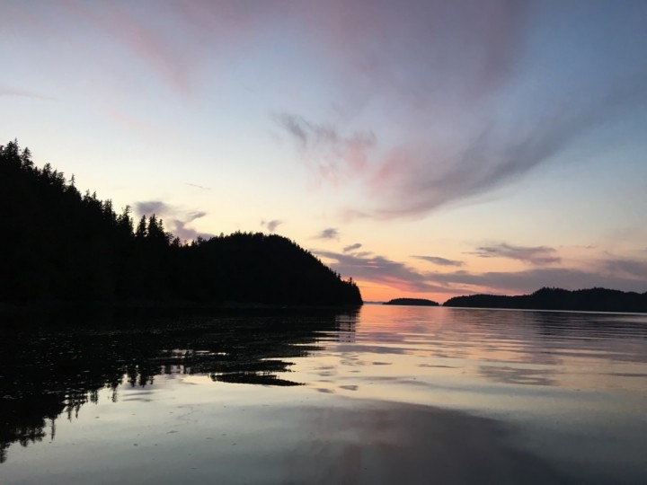 View from a shoreline of a vibrant purple and orange sunset.