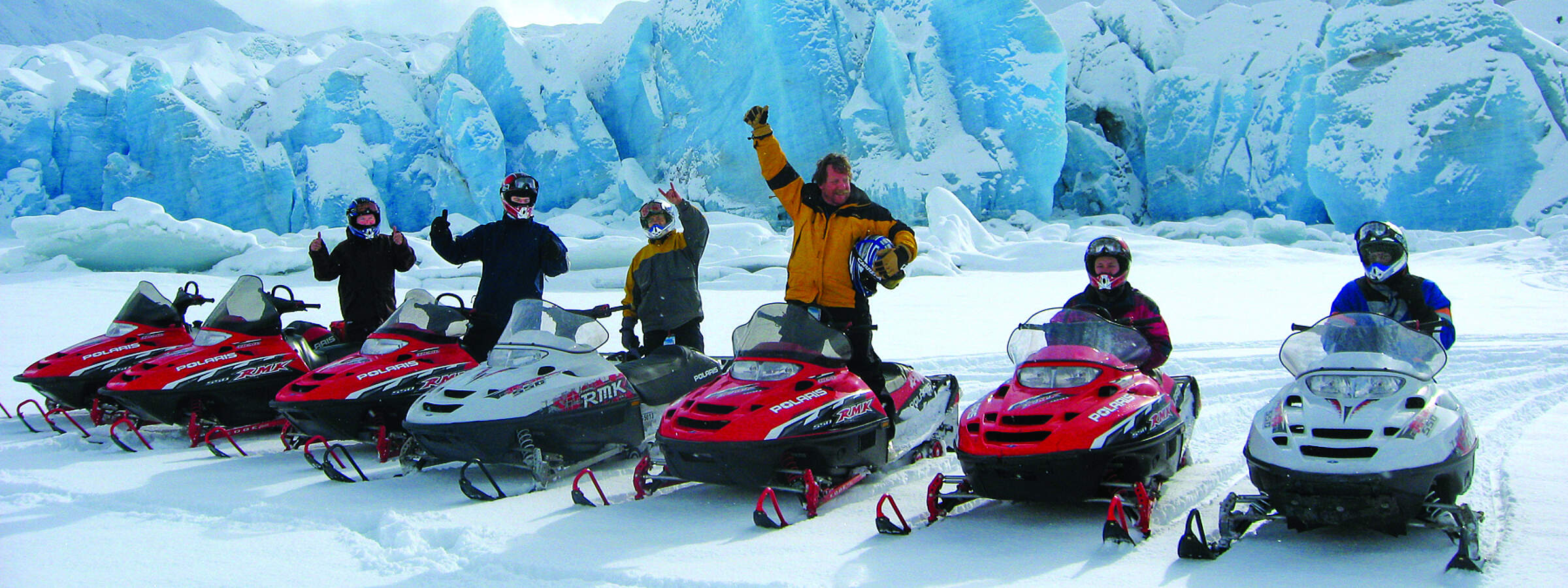 Snowmobilers take a pause in front of Spencer Glacier for a photo op