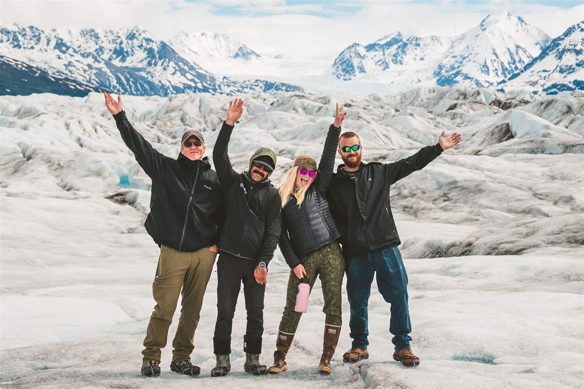 Pilots standing on an Alaska glacier wave at the camera