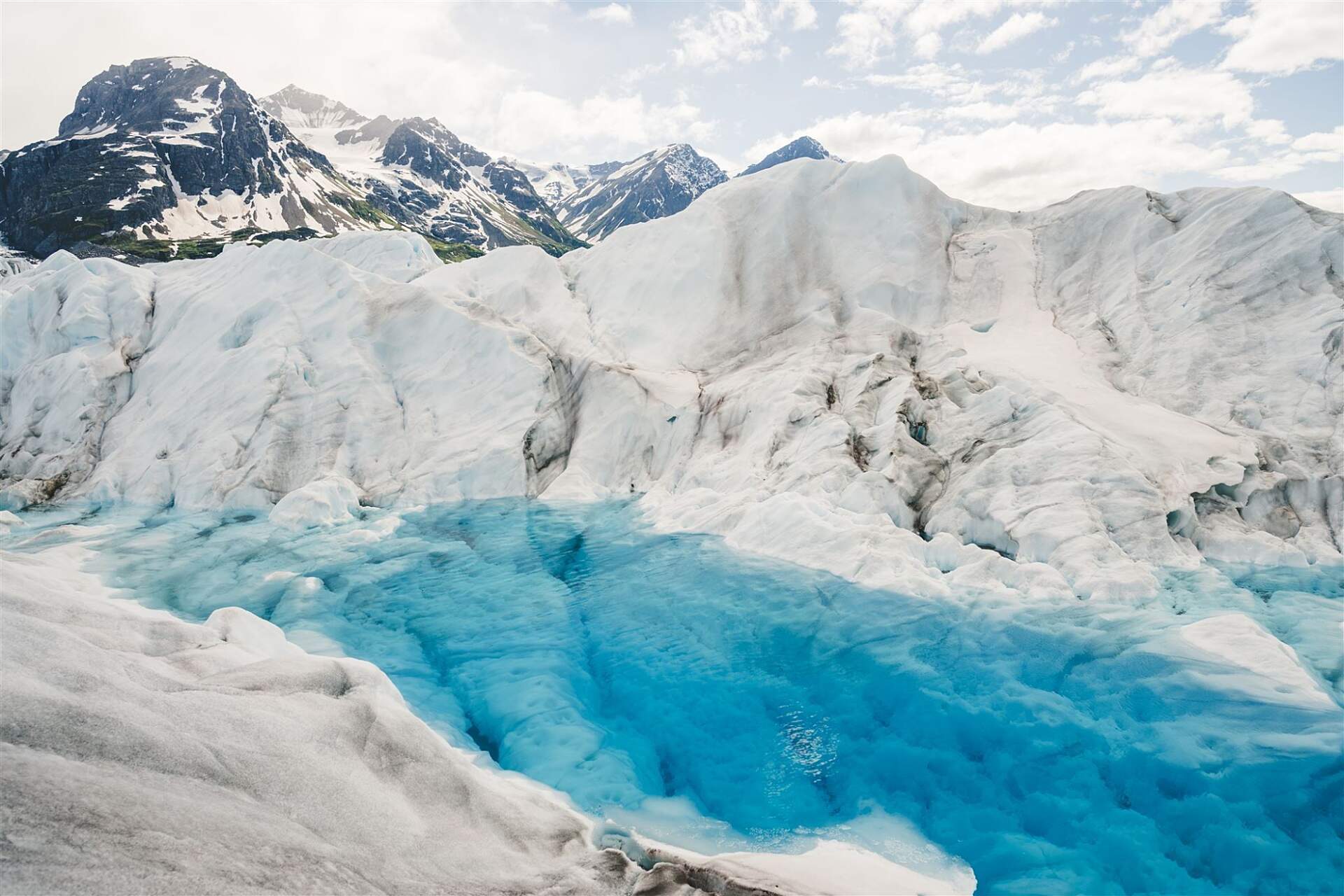 Brilliant blue glacier melt pool as seen from a helicopter tour with Outbound Heli Adventures