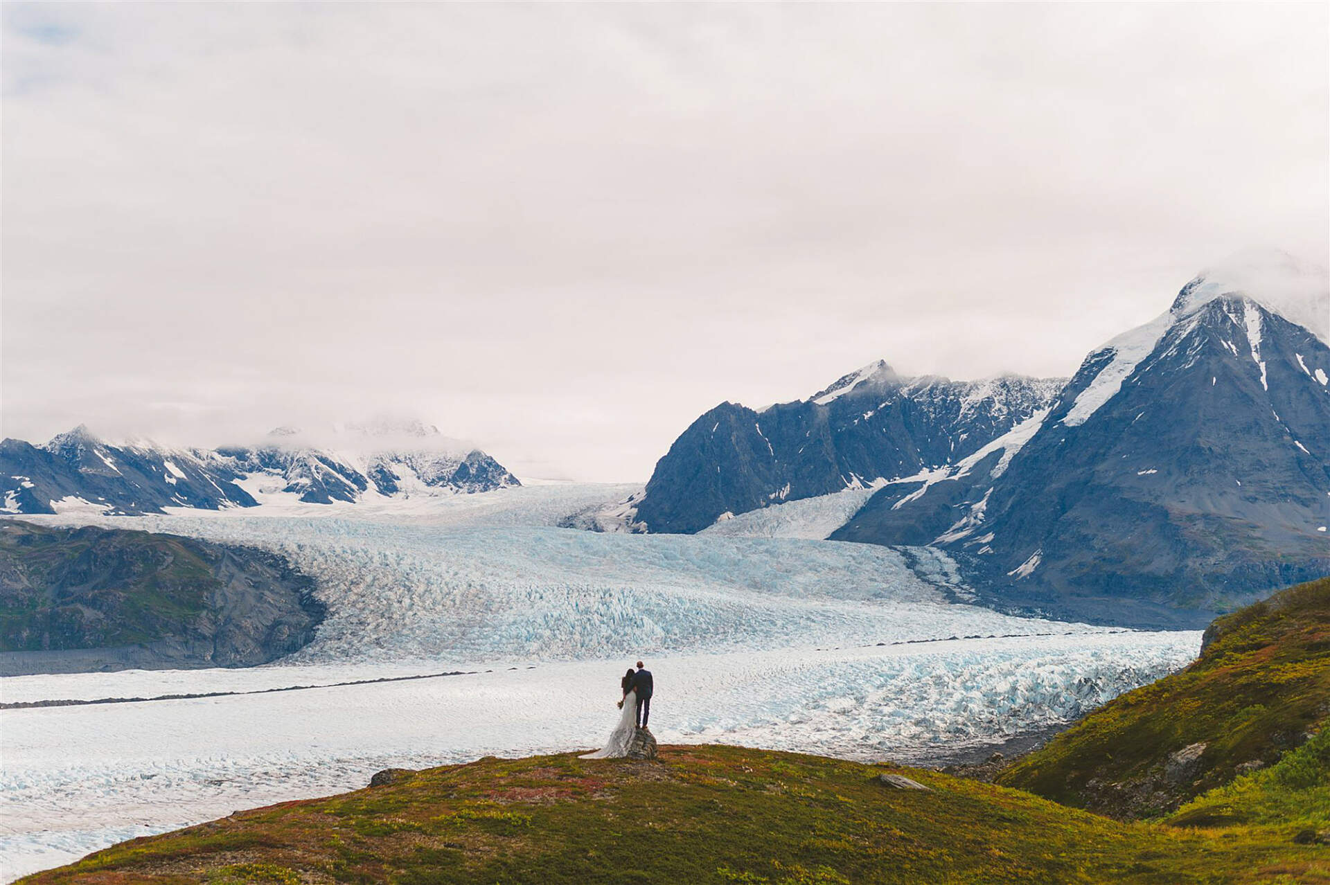 Couple getting married atop a mountain with a glacier in the background