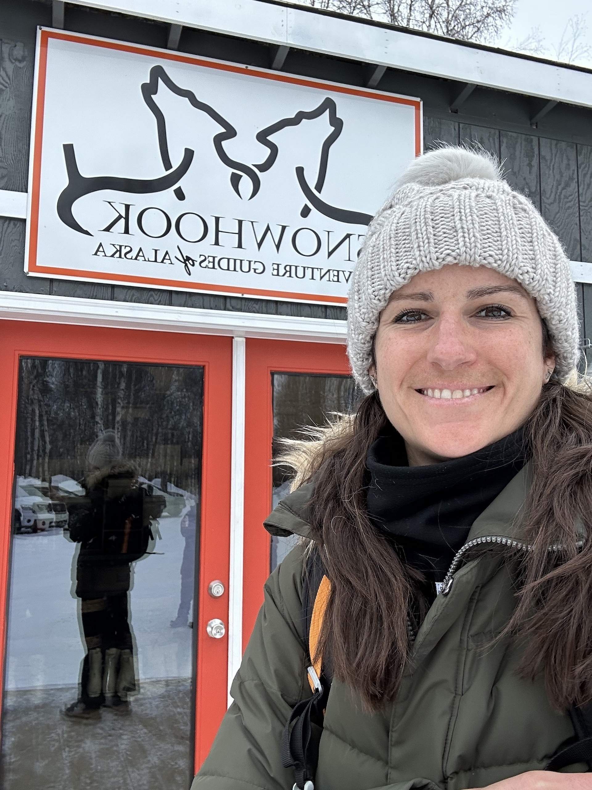 Jaime takes a selfie in front of the welcome cabin at Snowhook Adventure Guides of Alaska.