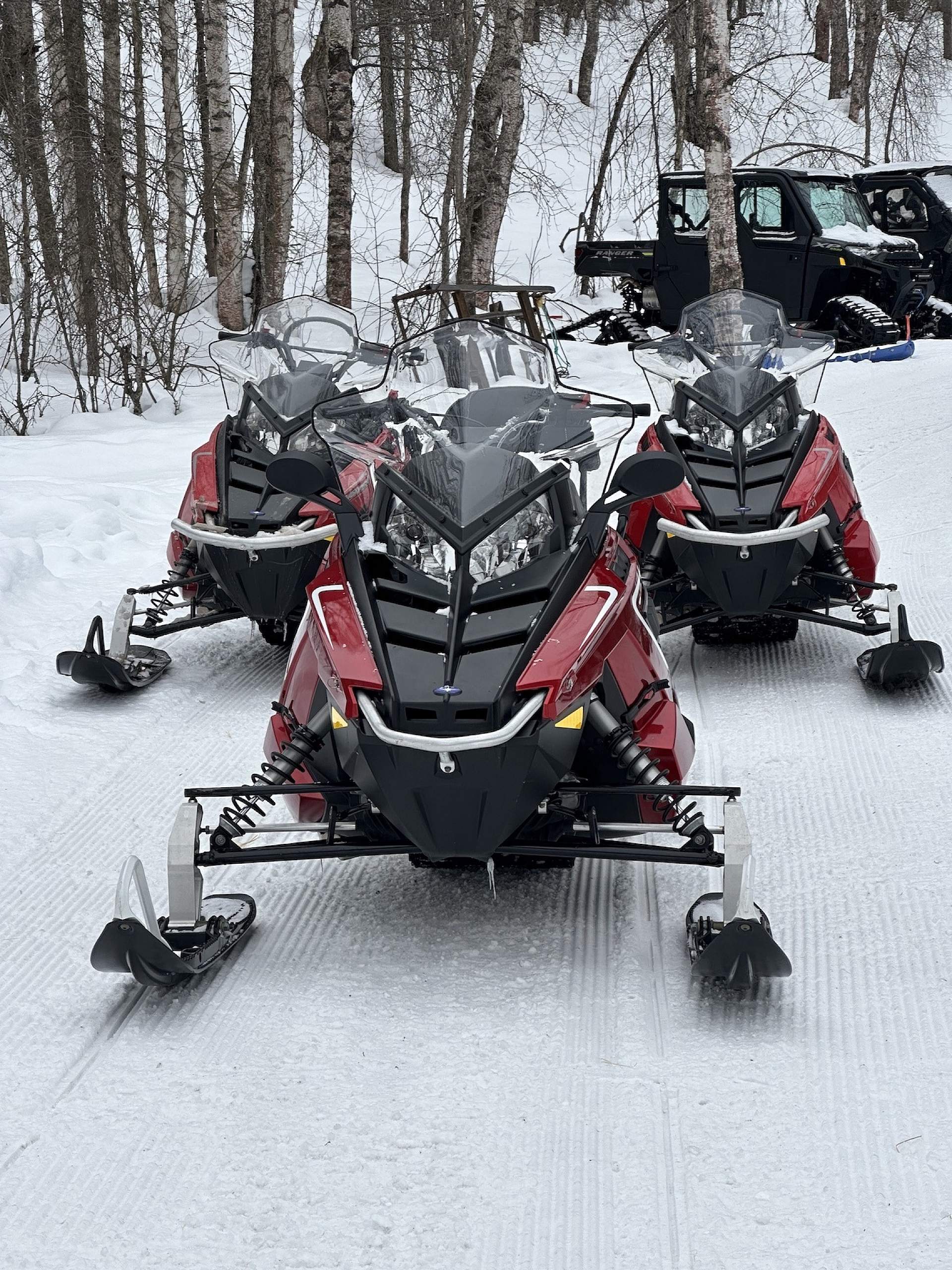 A group of snowmachines await their riders for a tour at Snowhook Adventure Guides of Alaska.