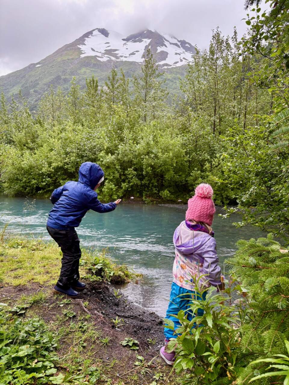 Kids throwing rocks into a glacial strem