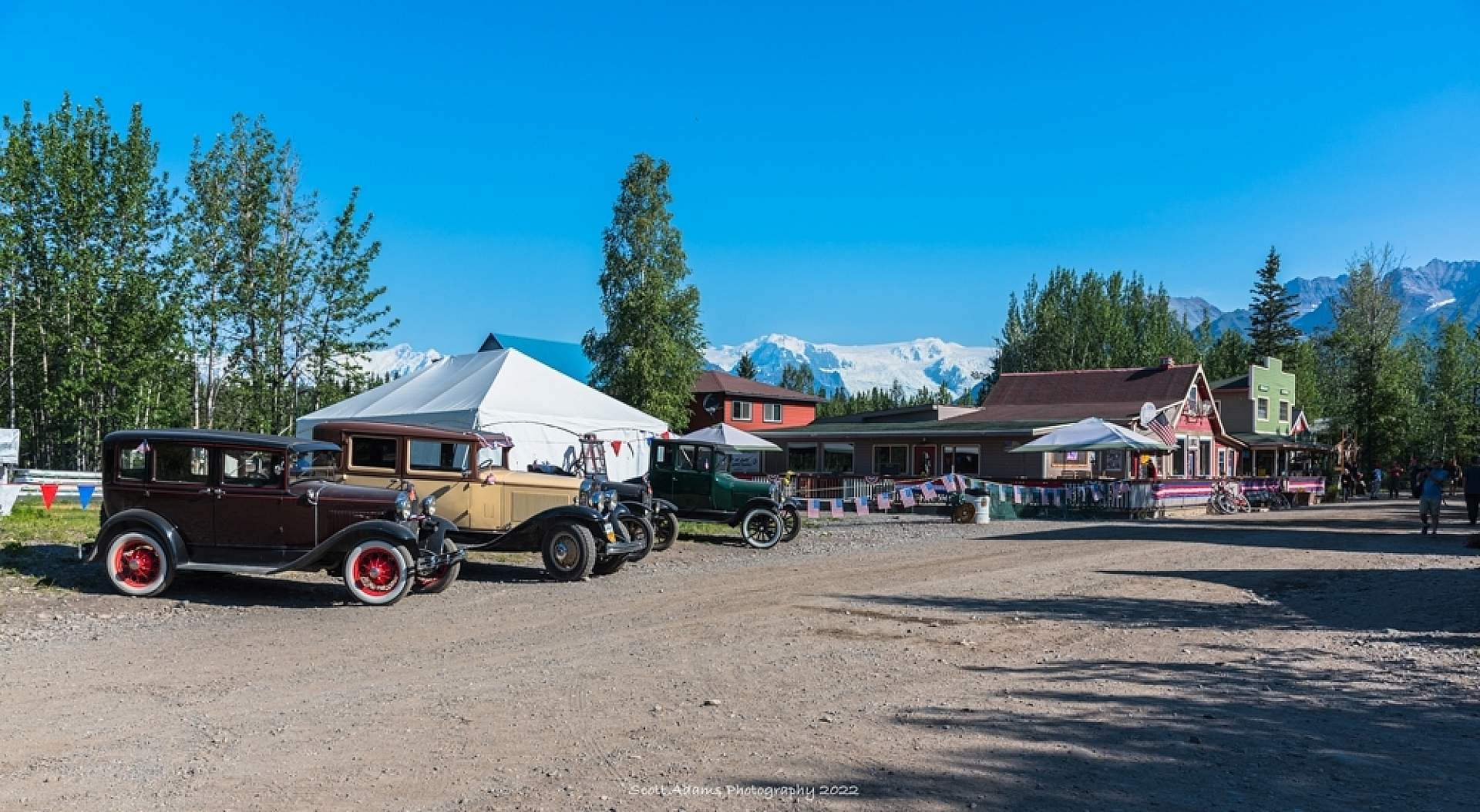Old-fashioned cars line the dirt road