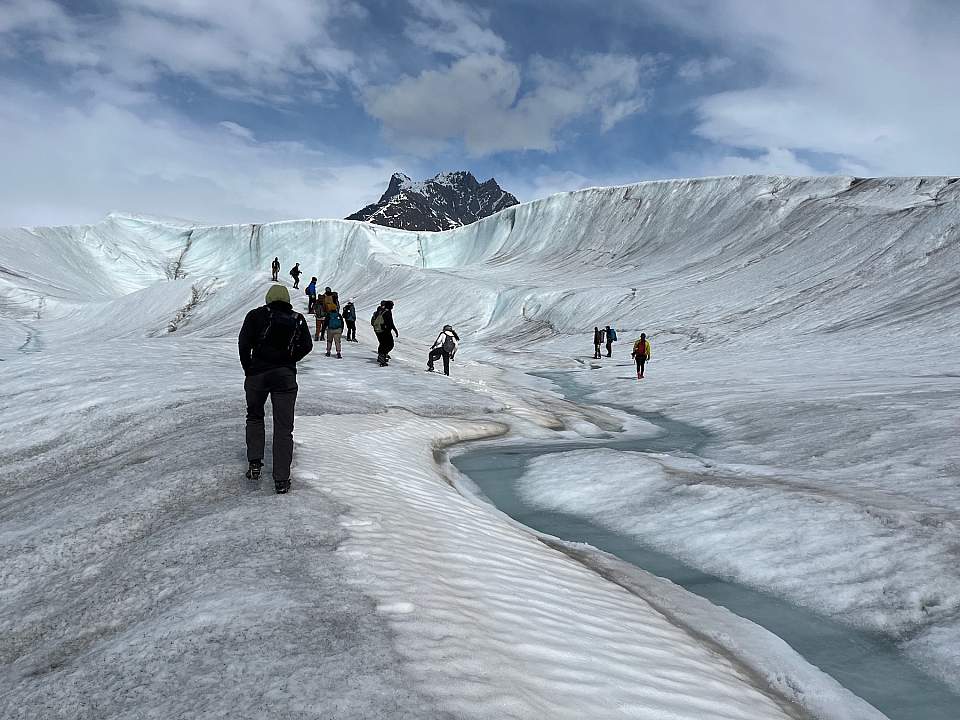 A group of hikers gather in a glacier valley
