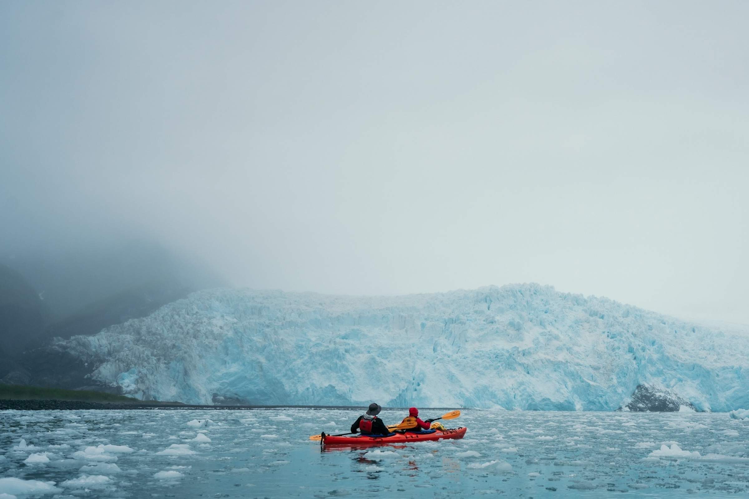 Kayakers pause in front of Aialik Glacier in Kenai Fjords National Park