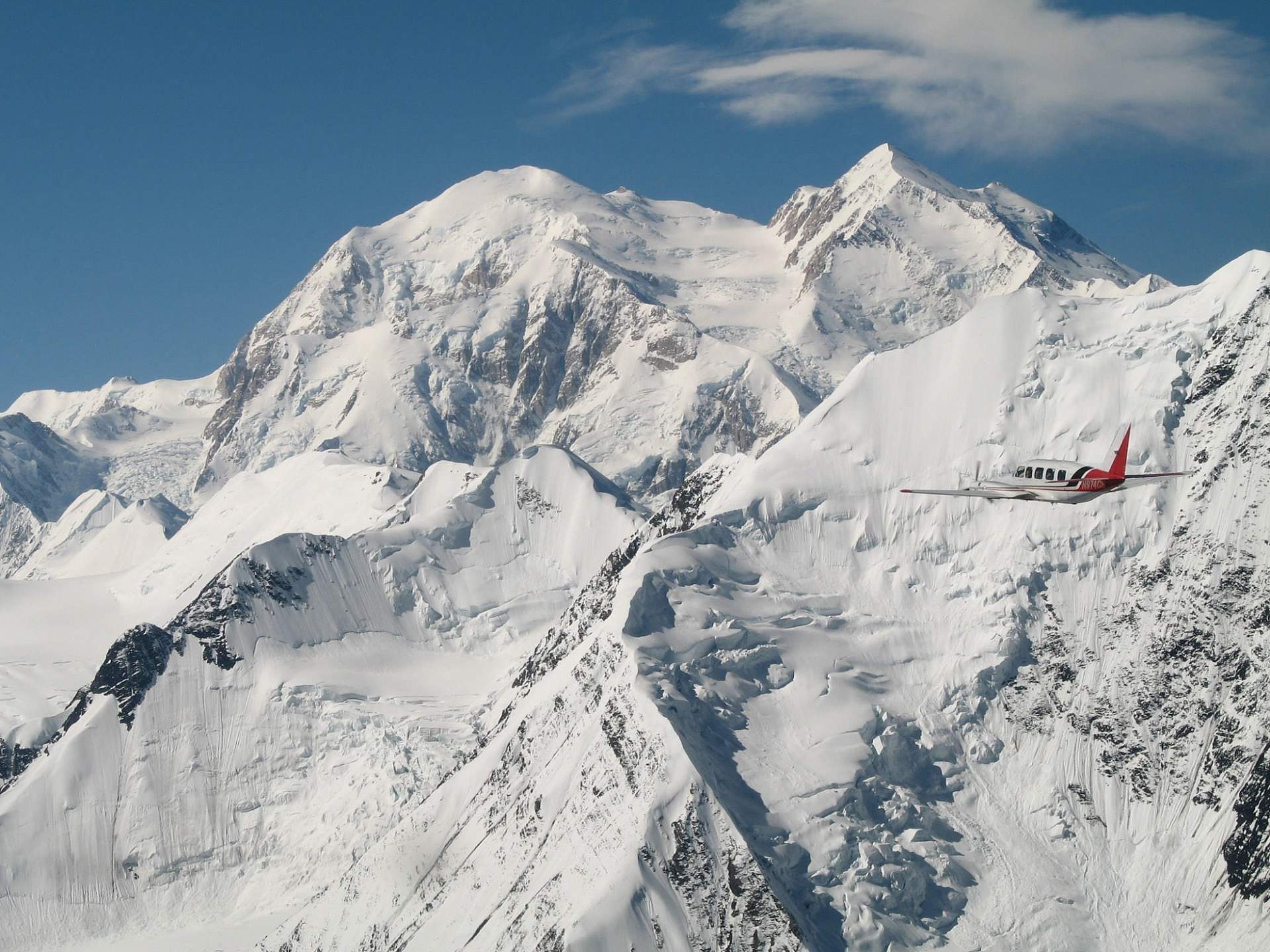 A flightseeing plane flies past snow capped Mt. Denali