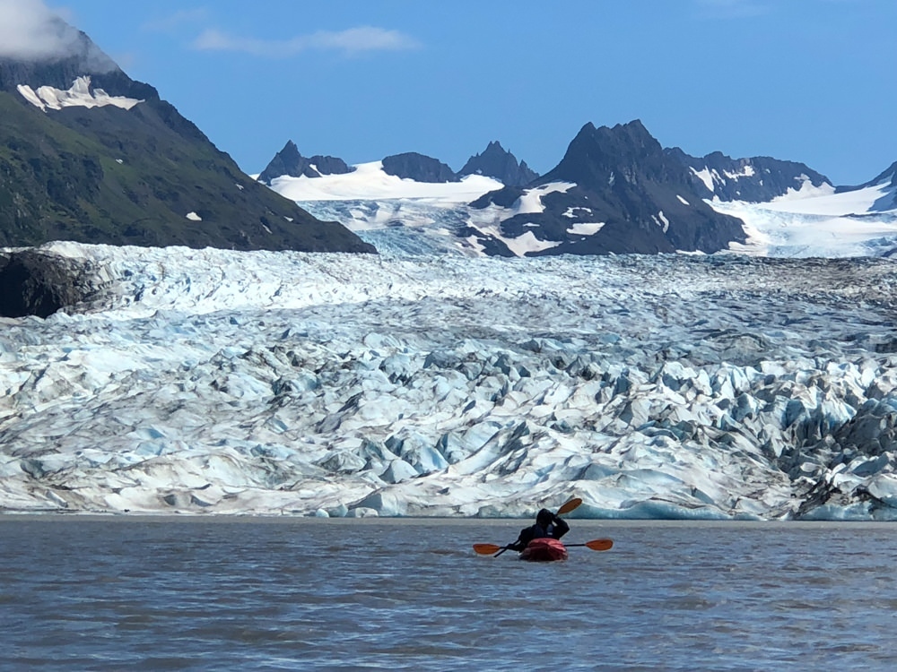 Kayakers on the water close to a glacier