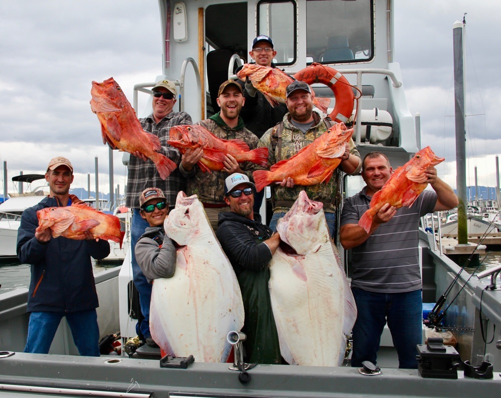 A group of people on a boat hold up fish they've just caught.
