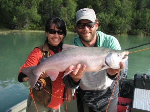 Two people in a boat hold up a fish they caught