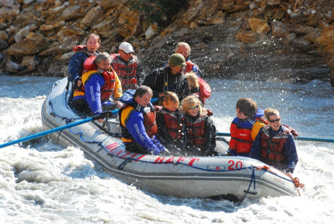 A group of people float down a choppy river on a raft