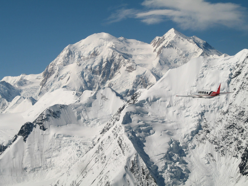 A flightseeing plane flies past snow capped Mt. Denali