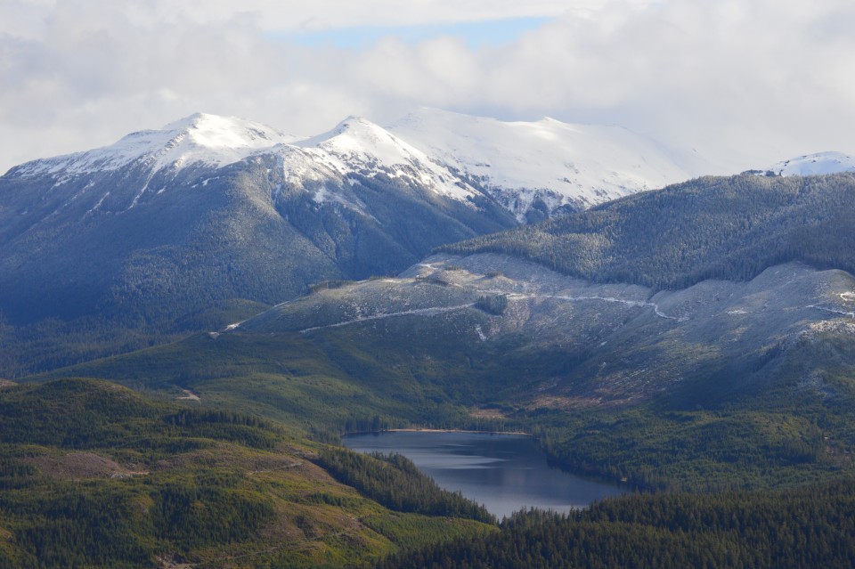 A lake with surrounding wilderness and snow capped mountains in the background on Admiralty Island