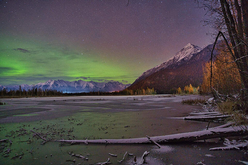 Green northern lights glow above the mountains near Palmer, Alaska