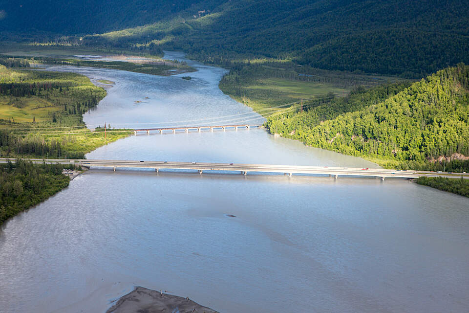 Cars drive over a bridge over the Knik River on a sunny summer day in Palmer, Alaska
