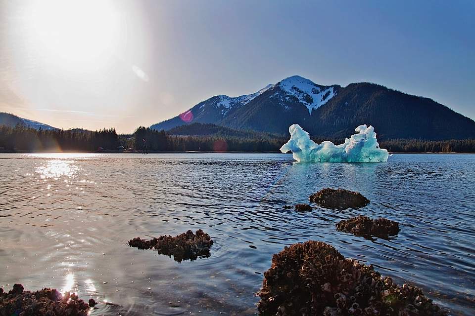 A giant iceberg that's broken off of LeConte Glacier floats in the water on a sunny day.