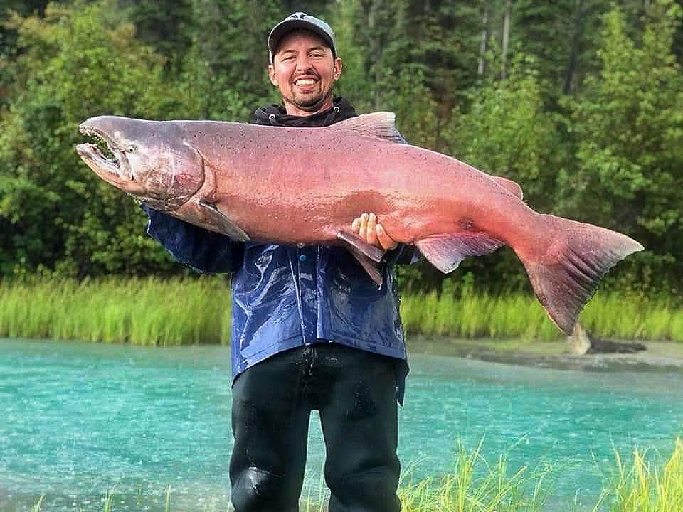 Man holds monster king salmon in front of river