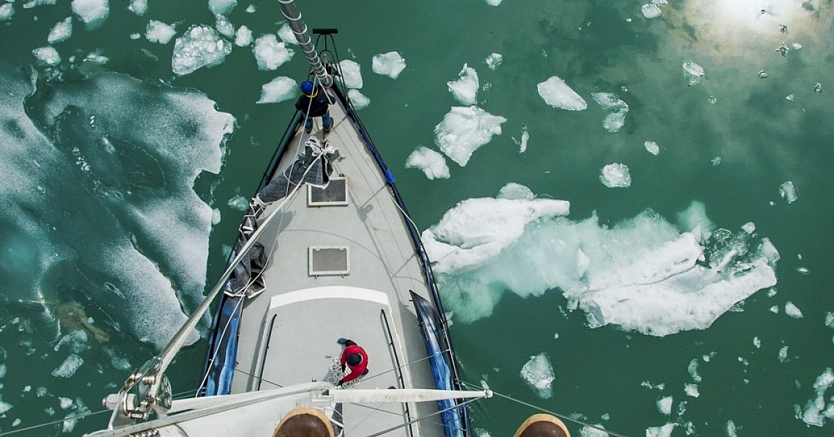 Crows nest view looking down at a steel sailboat in icy water