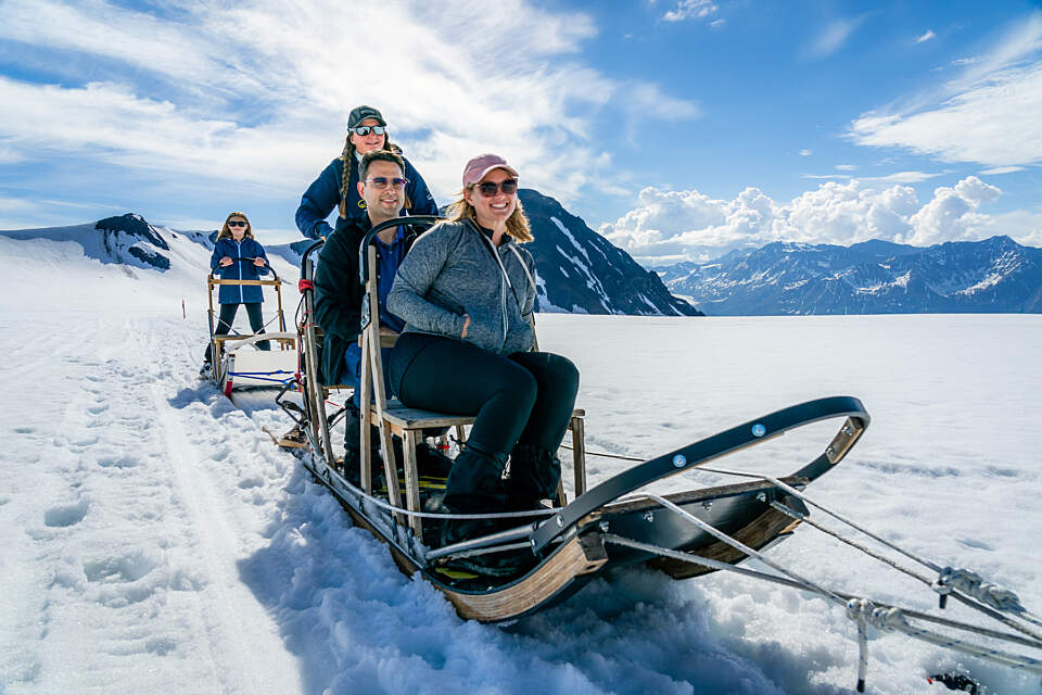 Guests sit on a dog sled on a glacier near Seward, Alaska