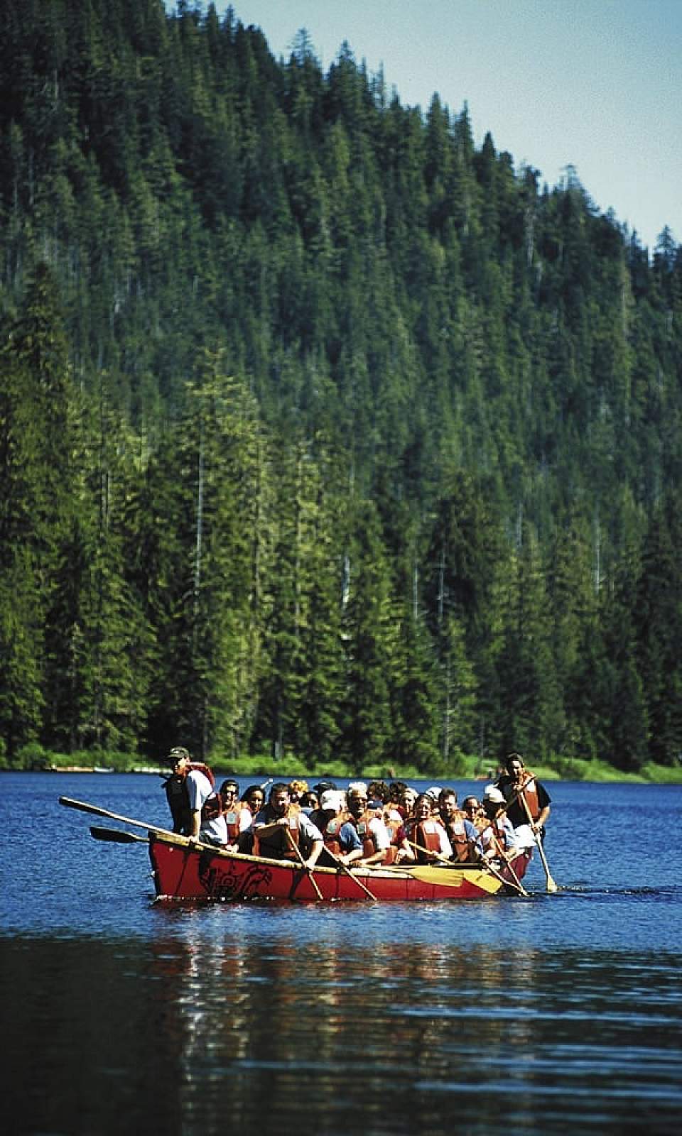 Paddle across a serene alpine lake in a traditional Alaska Native-style canoe