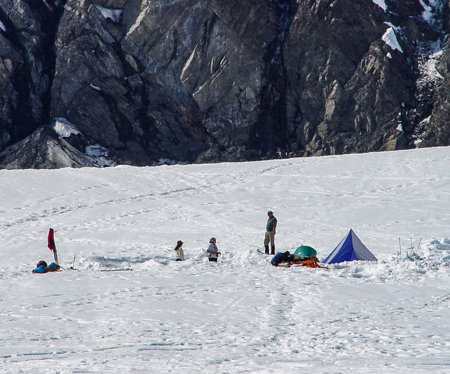 Hikers camp and explore on the snow with the Denali mountainside in the background.