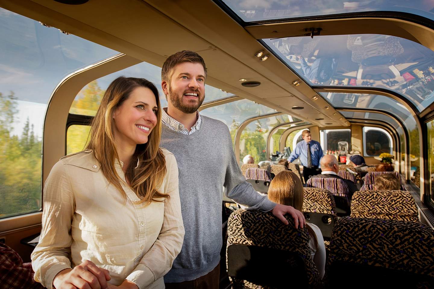 A couple enjoys looking out the windows of a train.