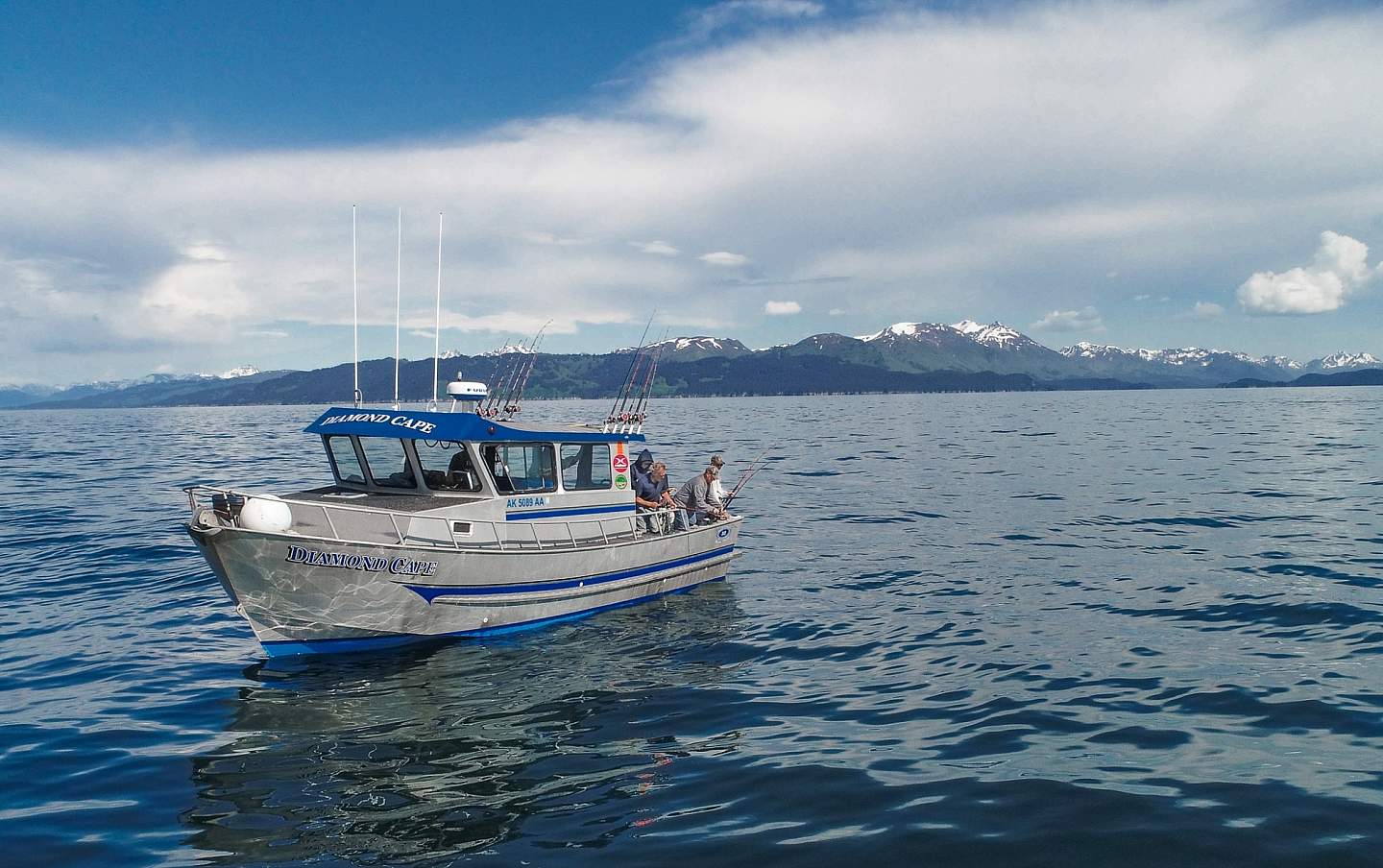 A small fishing boat on the water with mountains in the background.