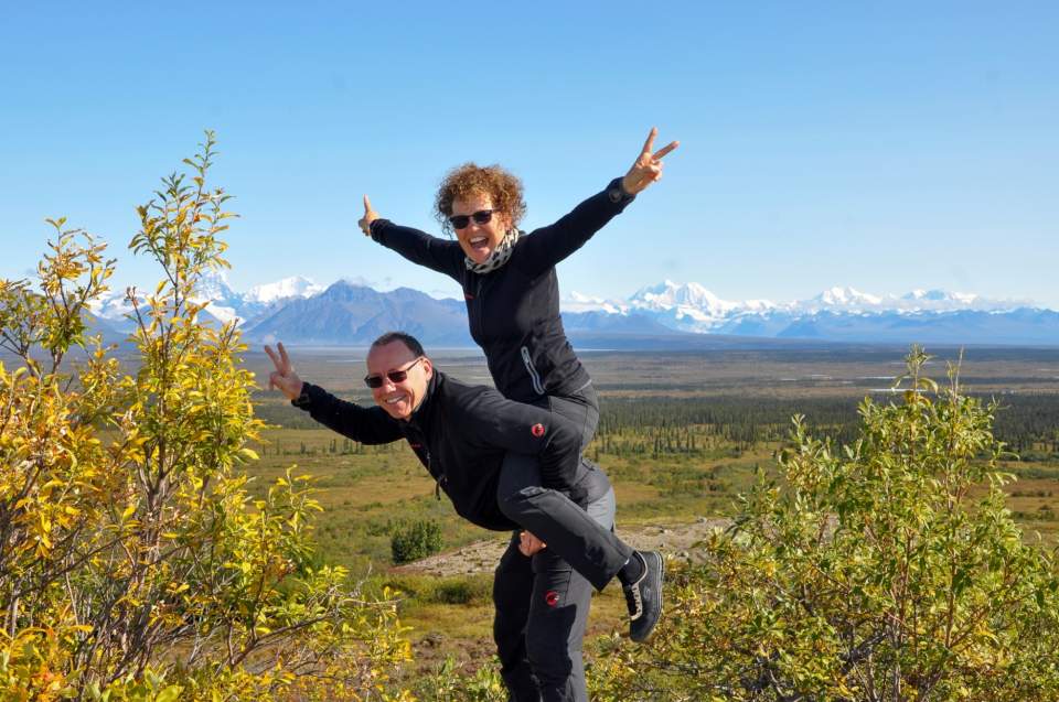 The owners Natalie and David pose in piggy back while outside on a summer day.