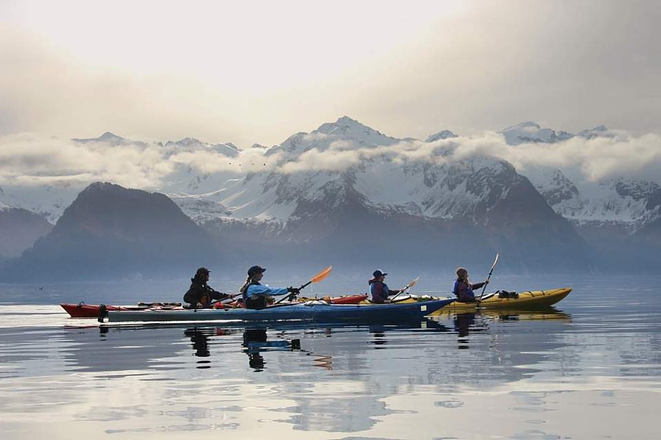 People kayaking in Alaska with mountains in the background.
