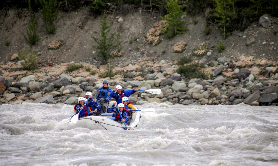 People rafting down a river on an inflatable raft.