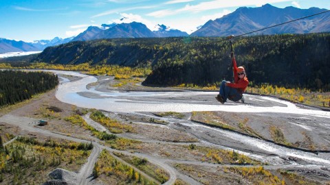 A person ziplining over an Alaskan valley.
