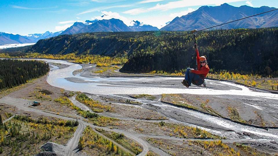 A person ziplining over an Alaskan valley.