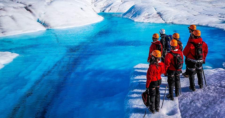 Hikers gaze at rich blue color of glacial pool