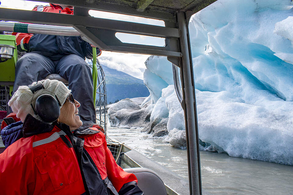 airboat passenger zooms by the bright blue face of the glacier