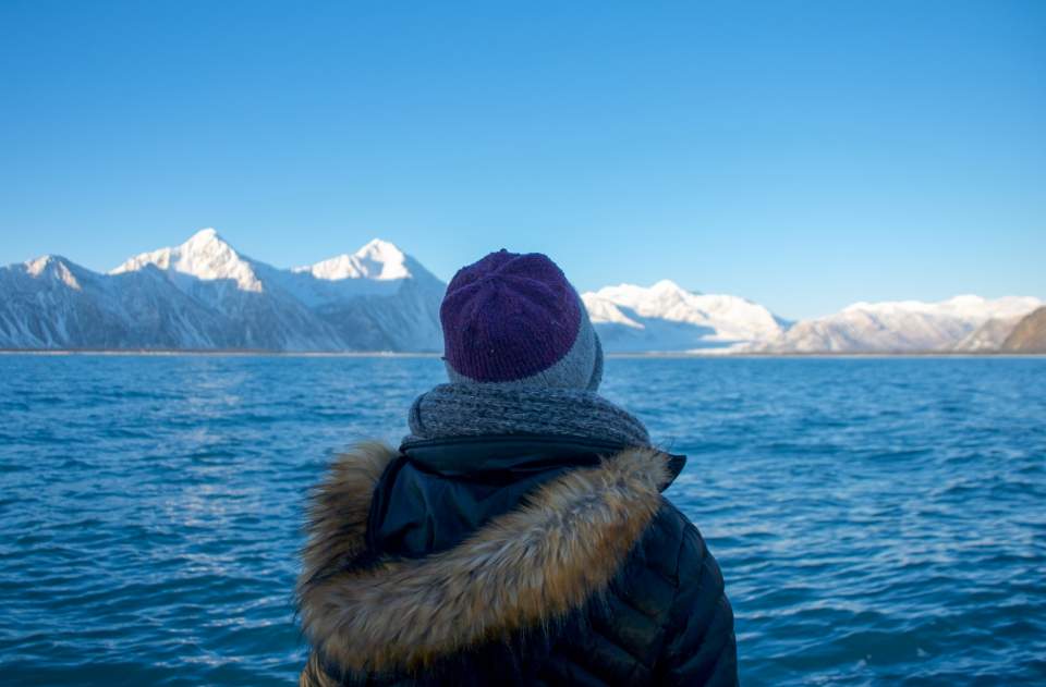 A small sightseeing boat cruises past a glacier.