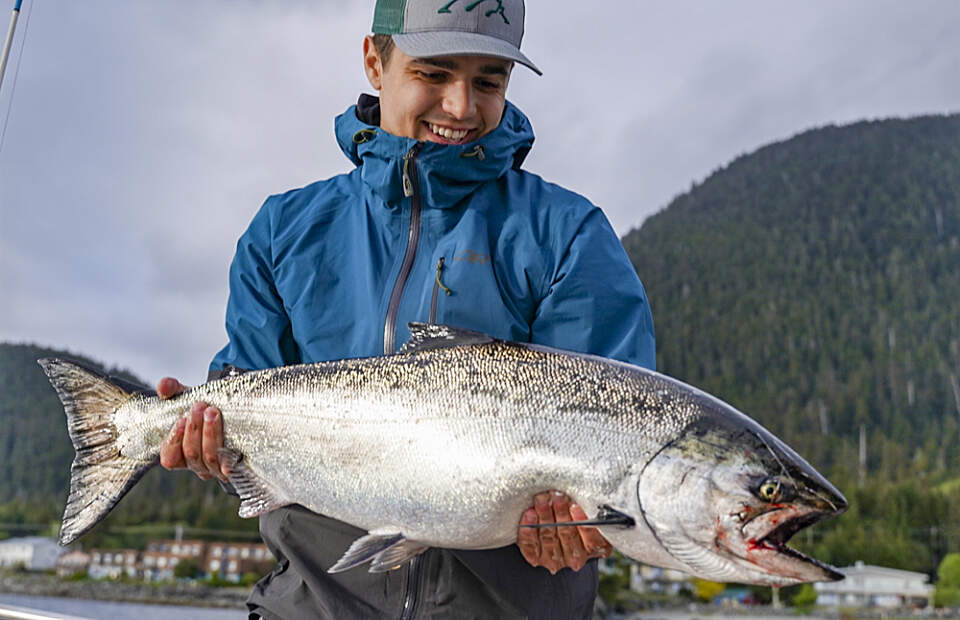 Man holding a salmon on a fishing charter with Sitka Expeditions