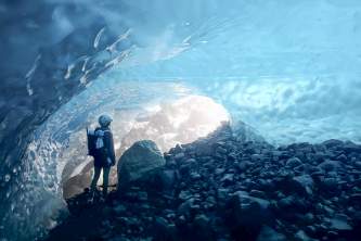 Person looking toward the exit of a bright blue ice cave Anya Voskresensky