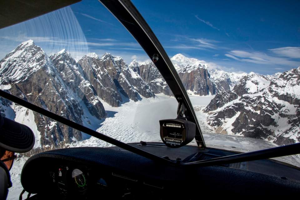 View from the cockpit of a bush plane of snow covered mountains.