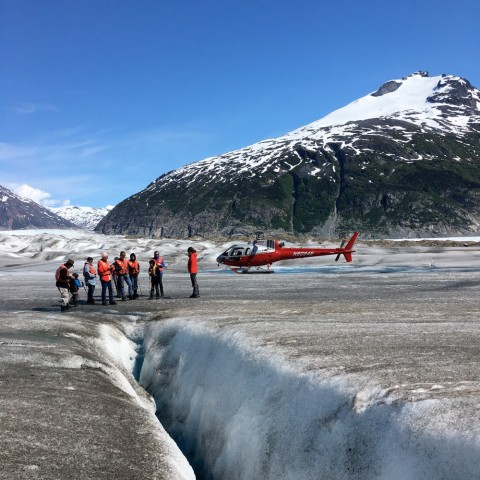 People walk on a glacier after landing by helicopter