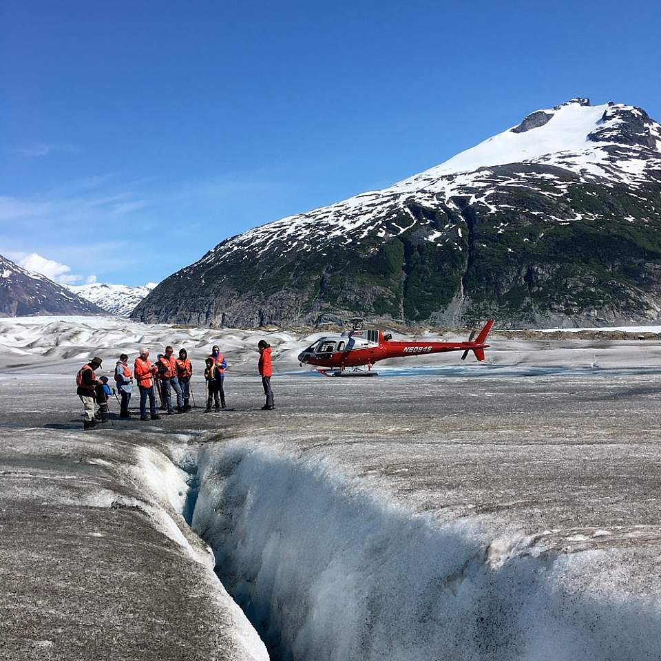 People walk on a glacier after landing by helicopter