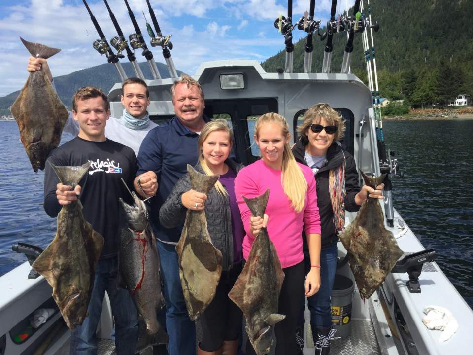 A family aboard a fishing boat hold up the fish they caught.