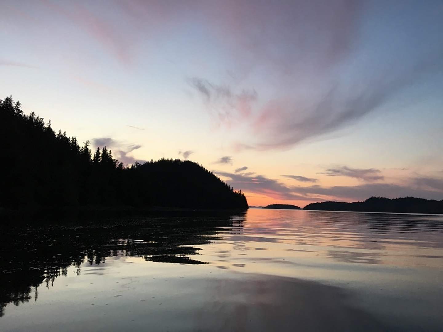 View from a shoreline of a vibrant purple and orange sunset.
