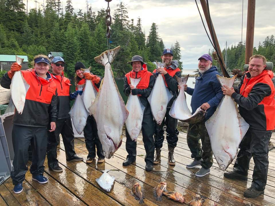 A group of people hold up fish that they've caught.