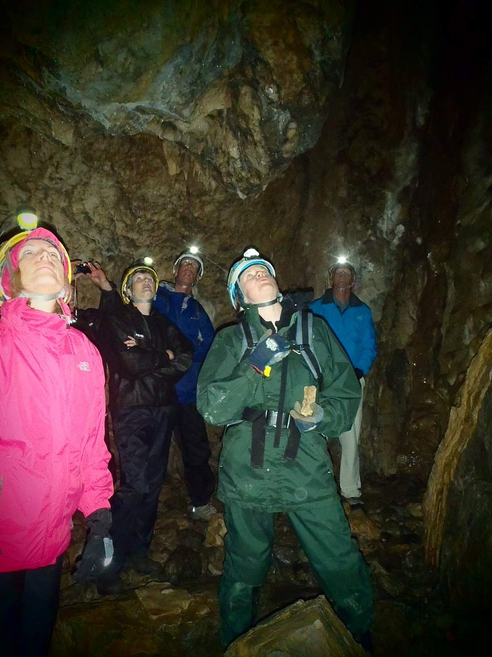 A group of people with helmets and headlamps explore a cave.