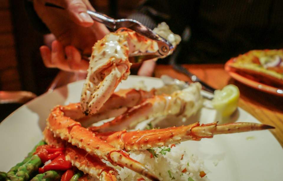 A dinner plate featuring crab legs with a side of rice and asparagus.