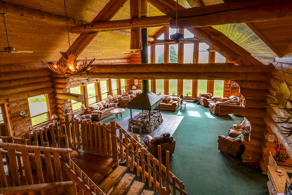 Interior view of Bear Track Inn with it's vaulted ceiling, large picture windows, and cozy log interior with a large central fire place