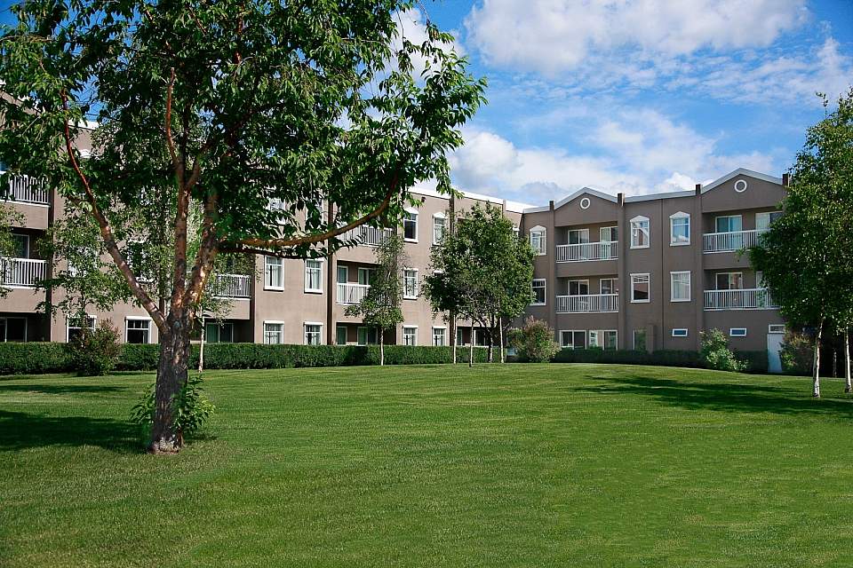 A hotel with a well landscaped lawn on a sunny day.